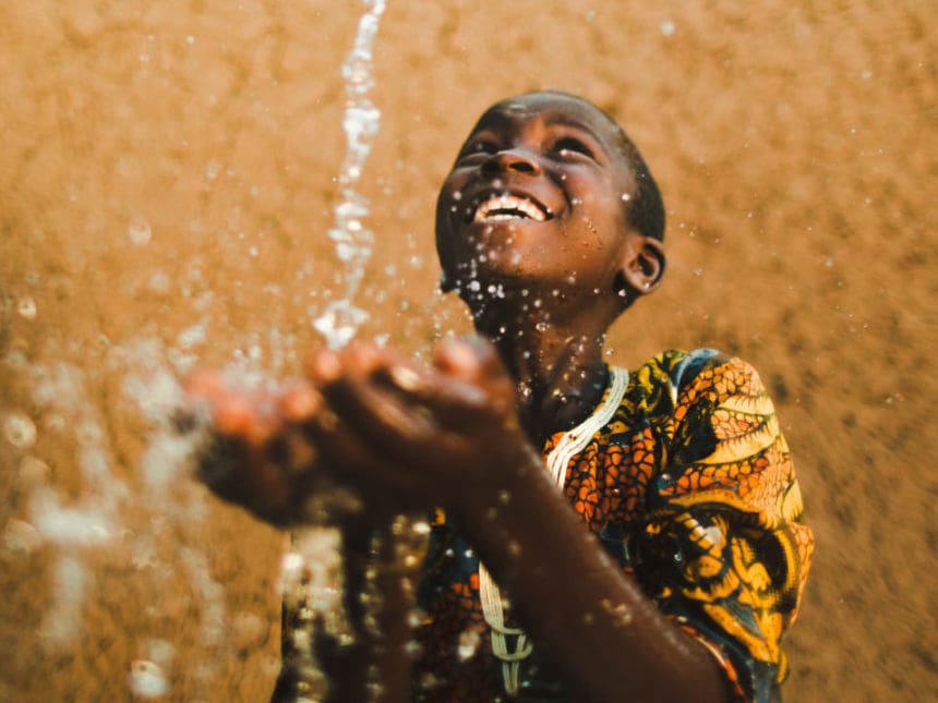 charity: water photo, boy enjoying clean water